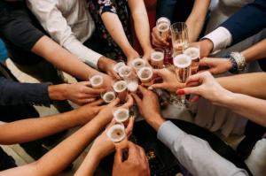 A diverse group of hands come together, each holding a glass of sparkling wine, in a toast
