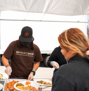 A volunteer distributes warm Thanksgiving meals to attendees at Eat & Be Well 2021