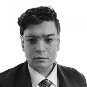 Devan Leos wearing a suit and tie and glasses in 2023