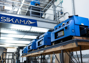 Interior of Sikama International, bright blue Falcon 5C machines in a row below a large Sikama International sign